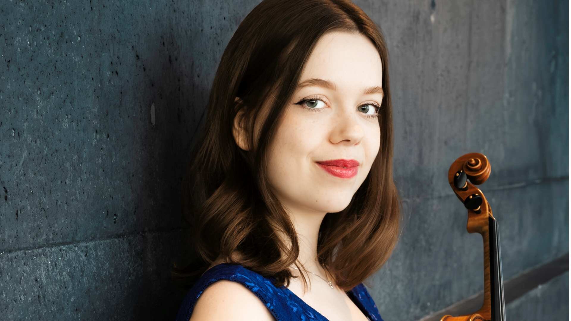 Bjargey Birgisdóttir in einem blauen Kleid mit Geige in der Hand